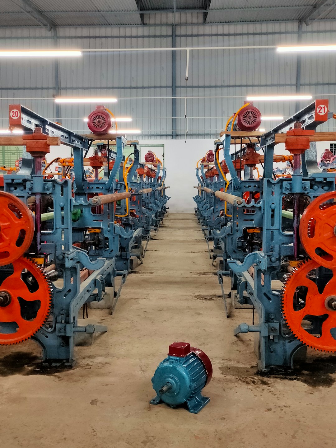 Rijen blauwe industriële textielmachines staan in een fabriek.